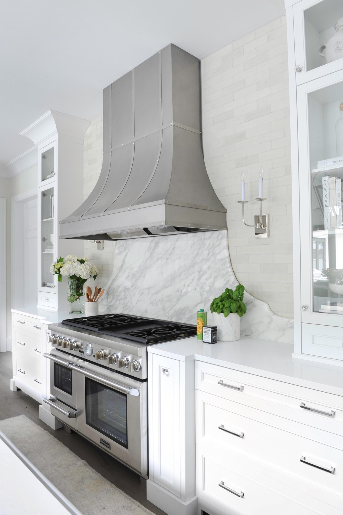 Range hood with matching duct cover extending upward over a cooktop.